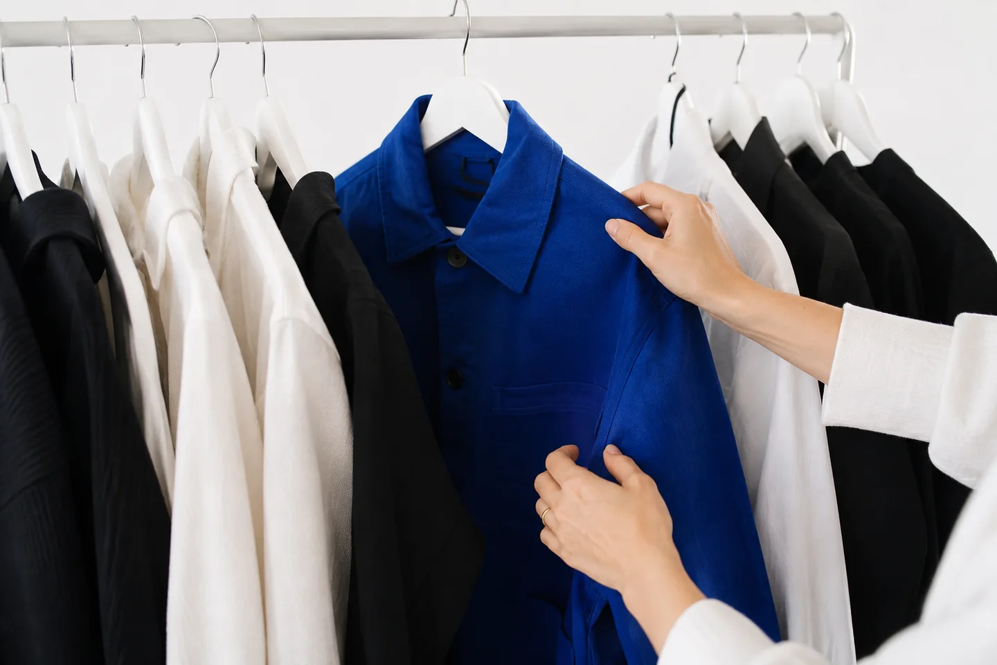 Hands styling a blue jacket for fashion content.