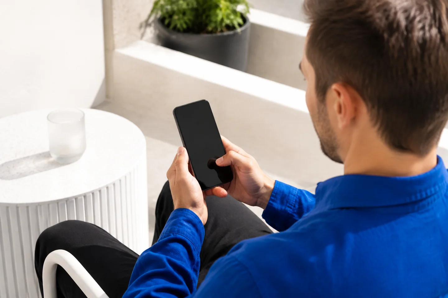 A person using a smartphone on a bright terrace.