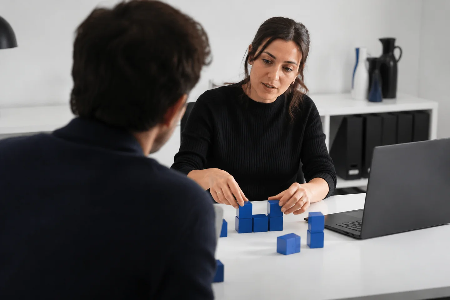 Two colleagues using physical blocks to discuss a software workflow.