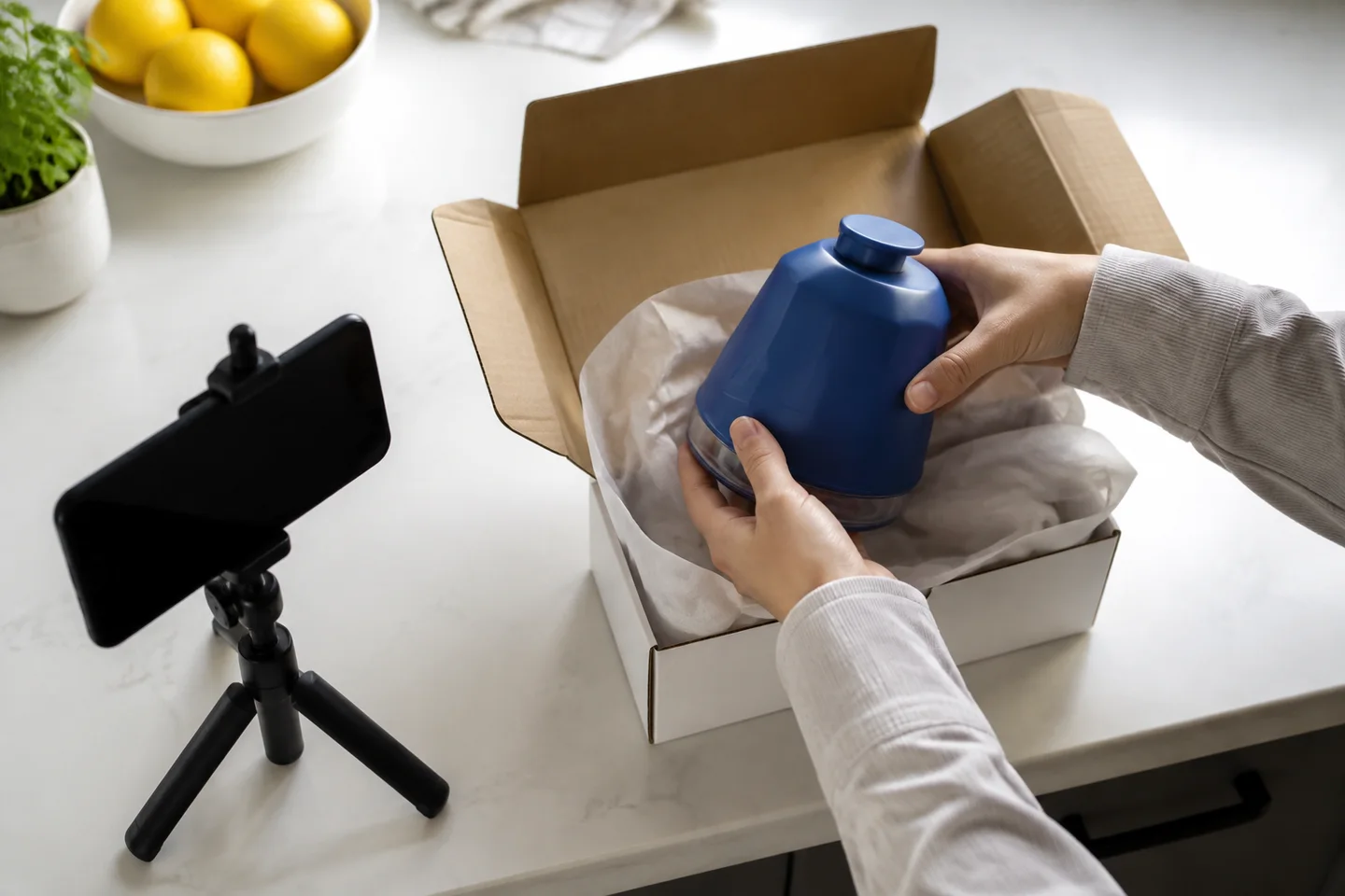 Hands filming an unboxing of a blue kitchen gadget.