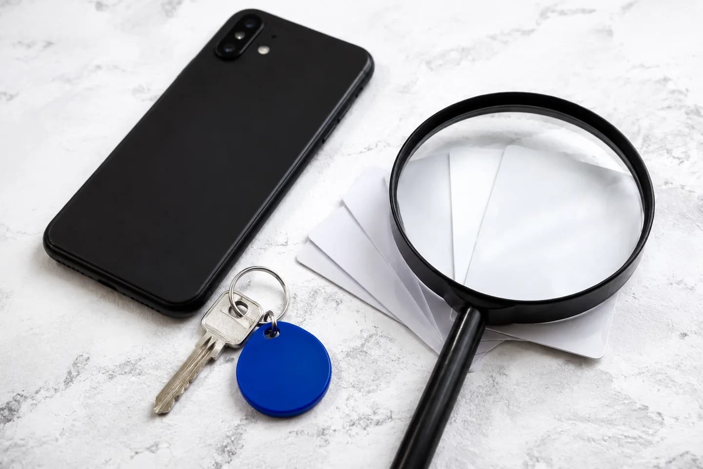 Phone, access cards and a key under a magnifying glass.