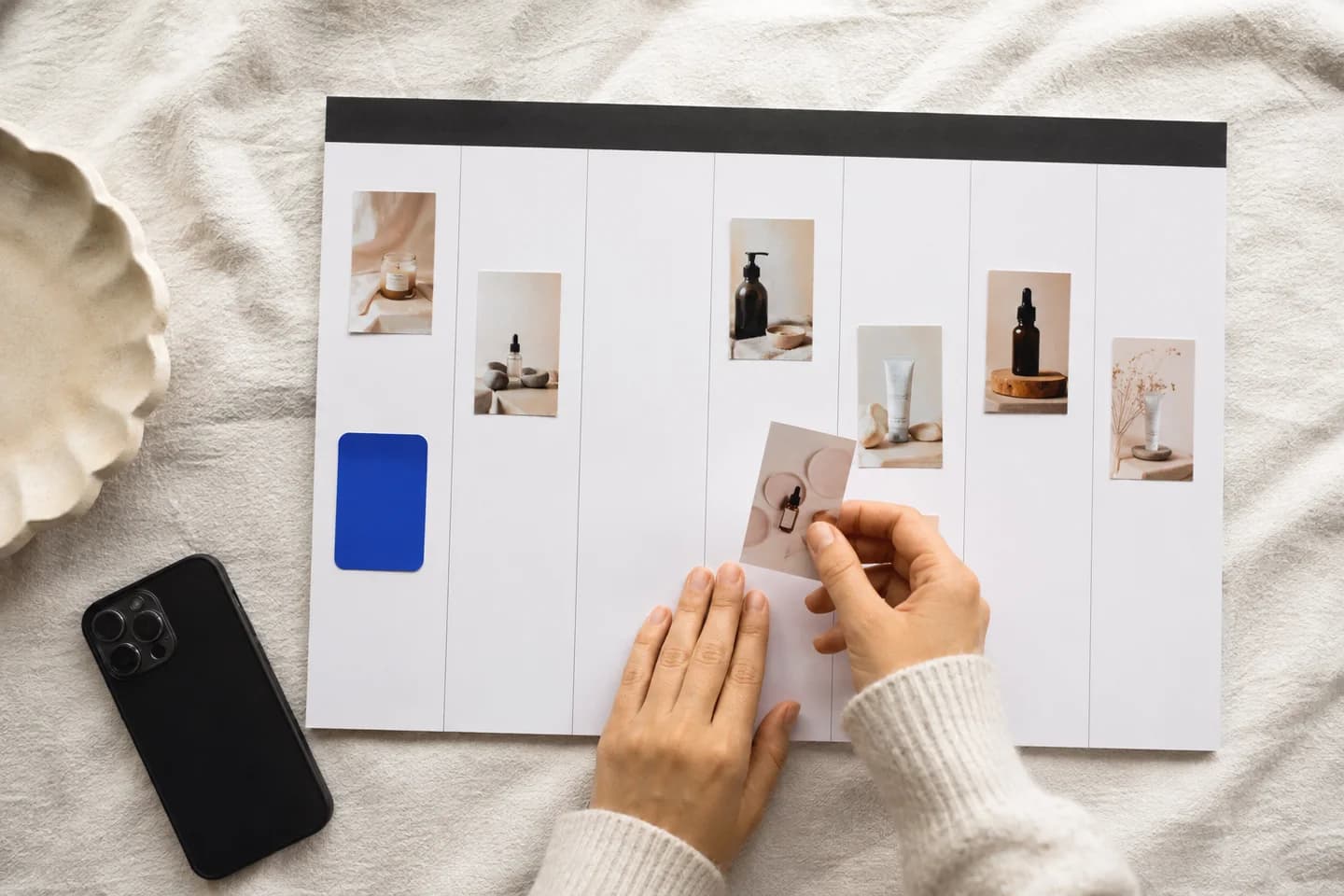 Hands arranging product photos into a blank weekly content planner.