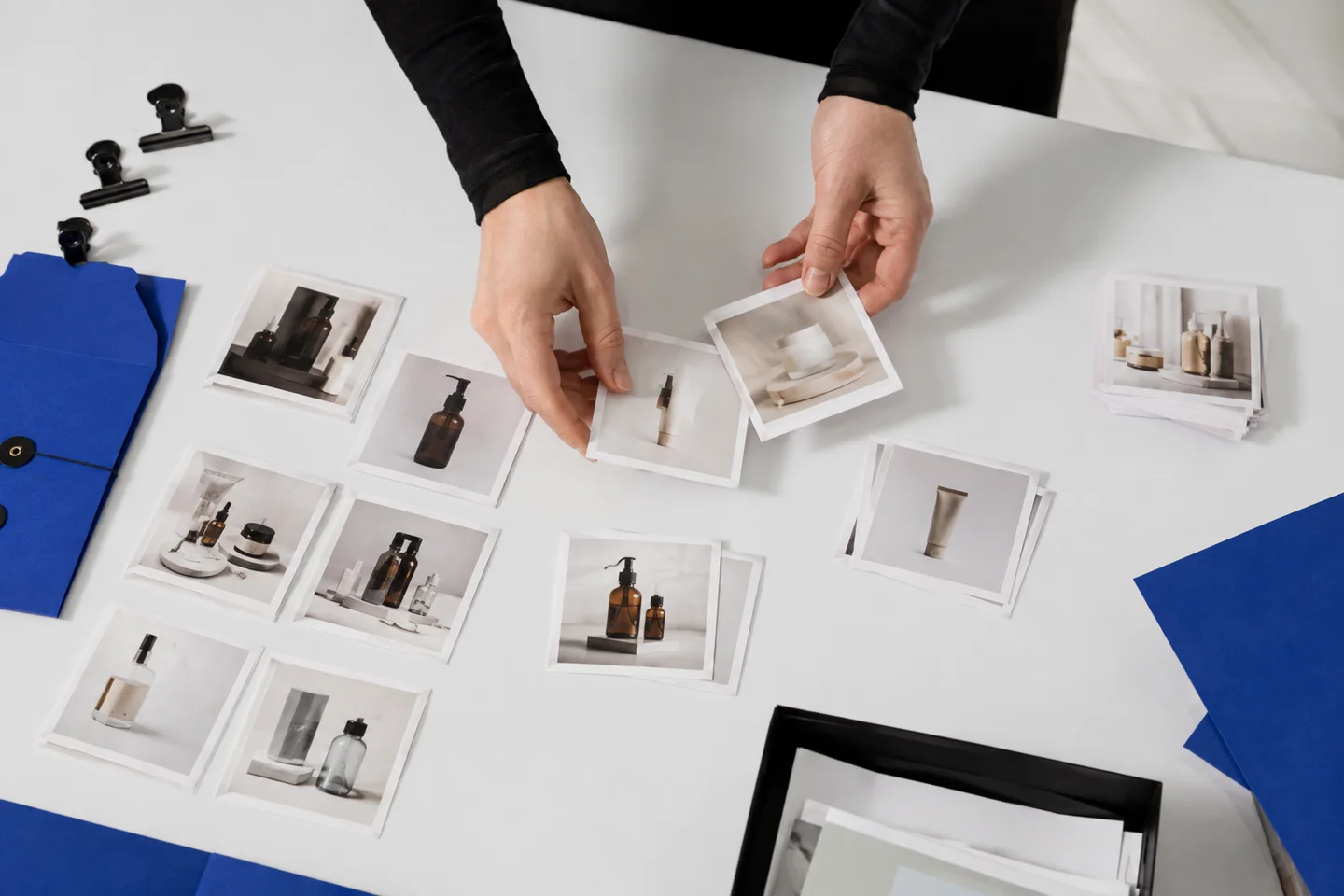 Hands sorting product photographs into organized content batches.