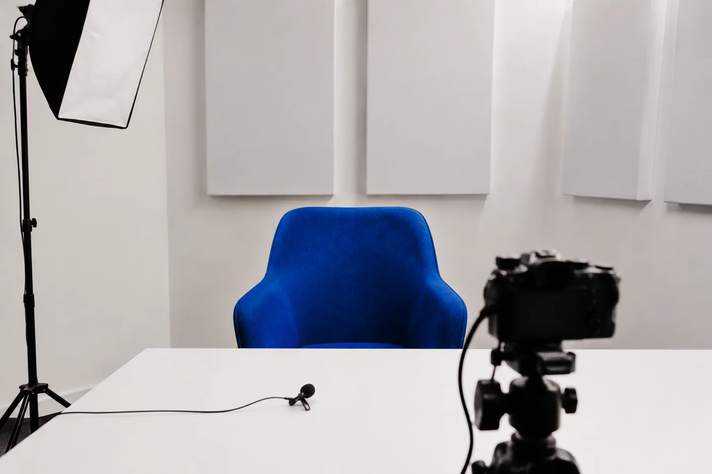 An empty presenter recording setup with a camera and blue chair.