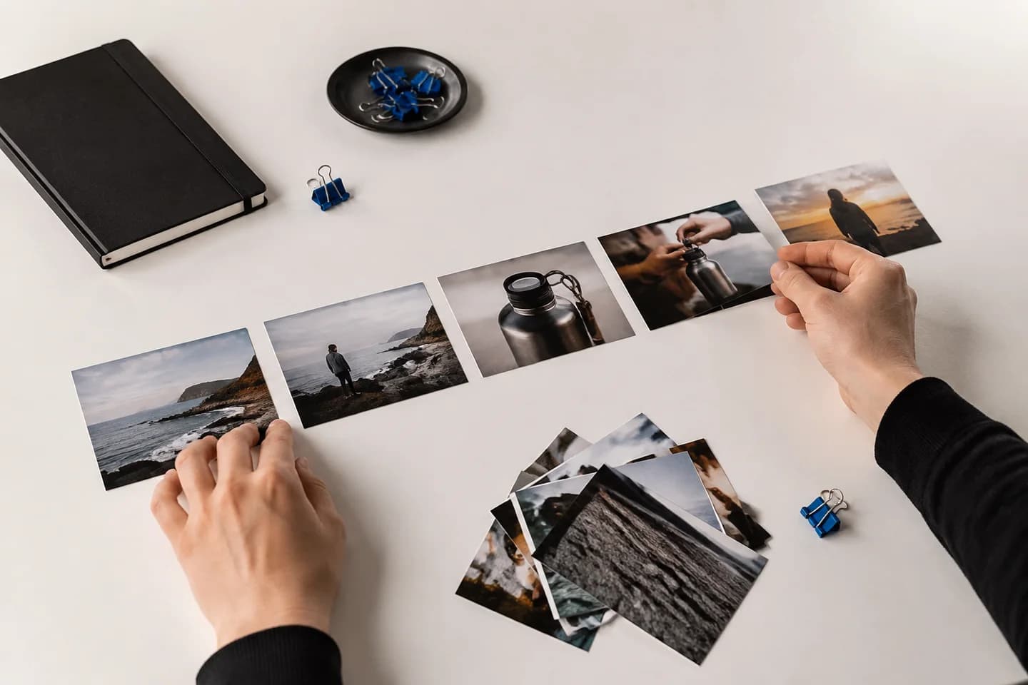 Hands assembling photographs into a video storyboard.