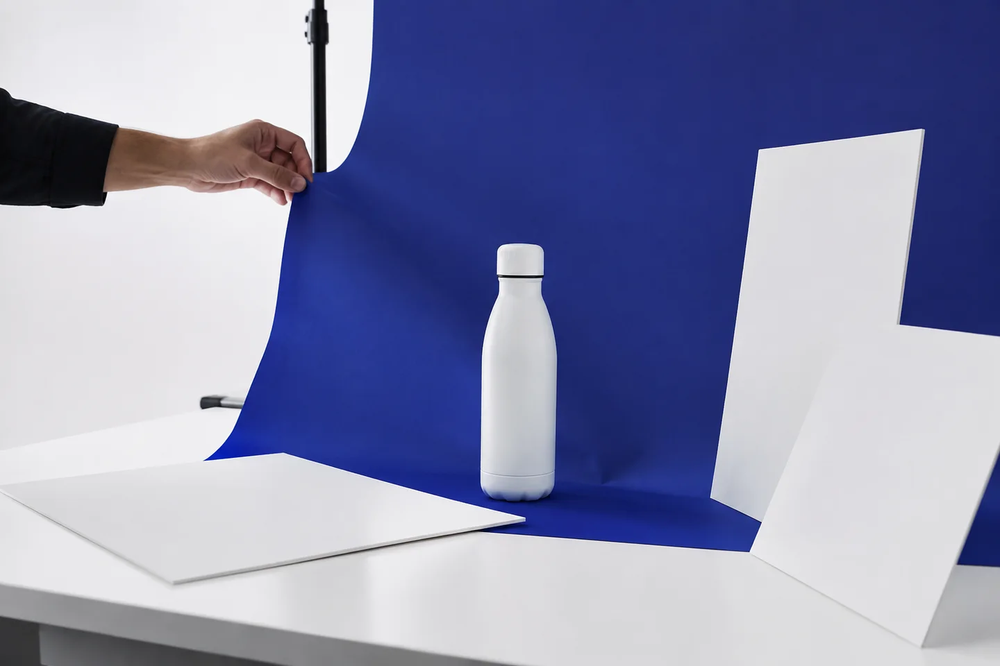 A photographer testing lighting angles around an unbranded bottle.