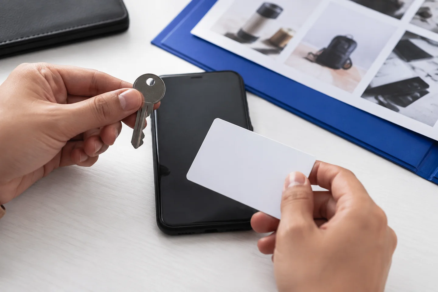 Hands check a key and access card beside a phone and asset history.