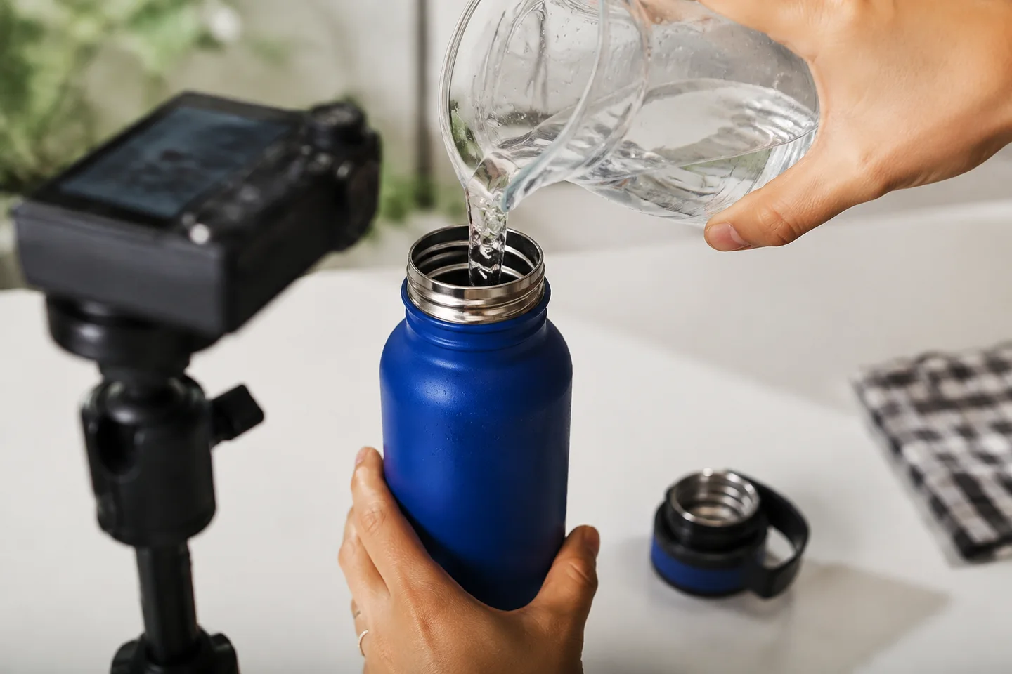 Hands fill a blue bottle during a faceless product demonstration.