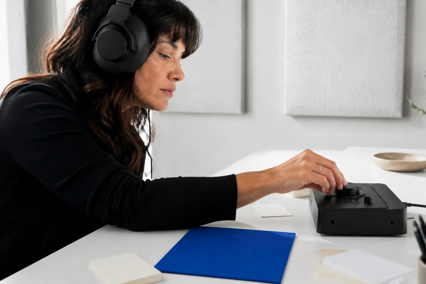 An audio editor listens closely while adjusting a control.