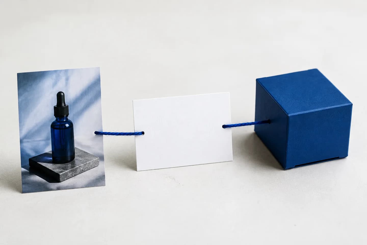 Blue thread connects a product photo, a blank card and a product box.