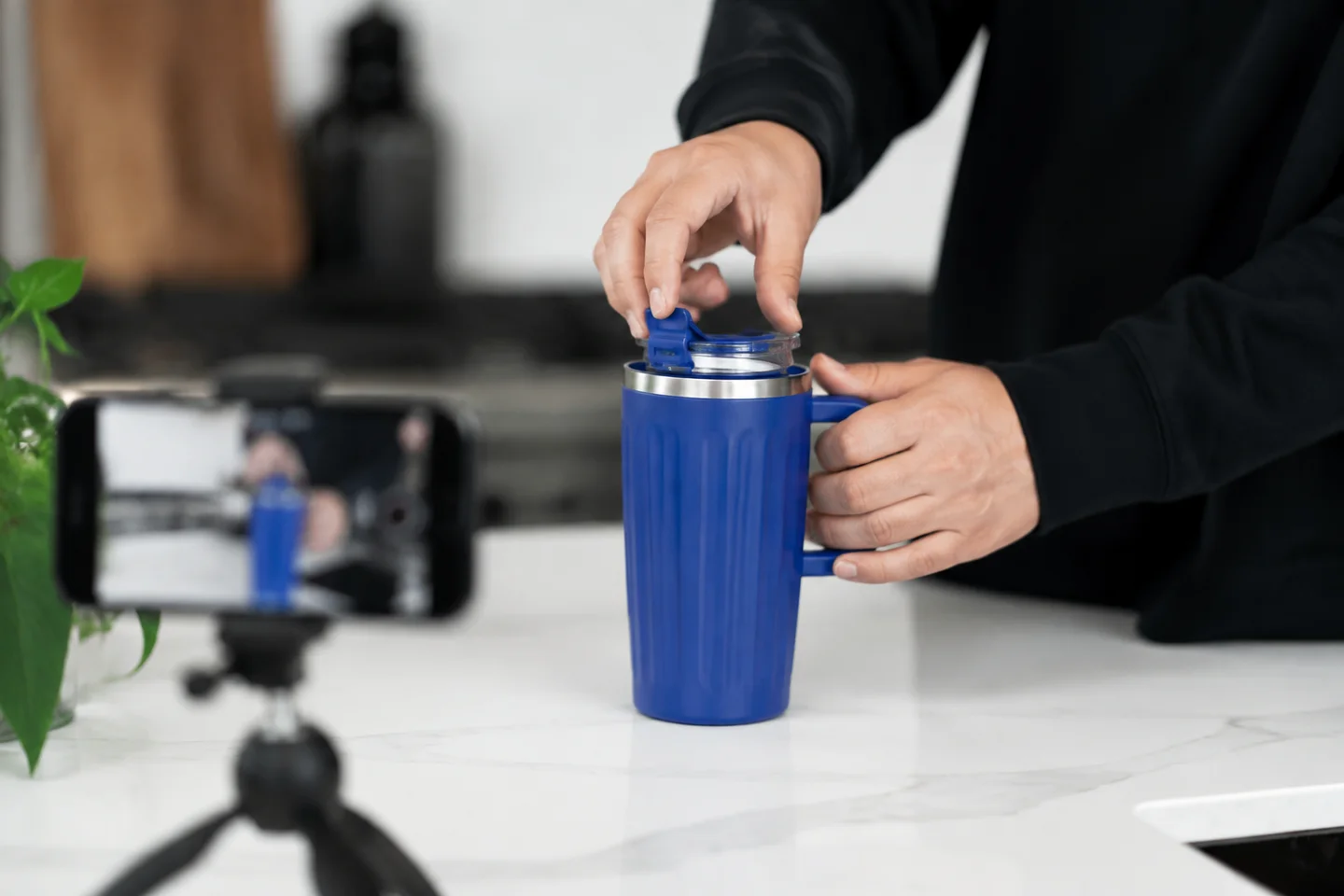 Hands demonstrating the lid of a blue cup for a close-up recording.