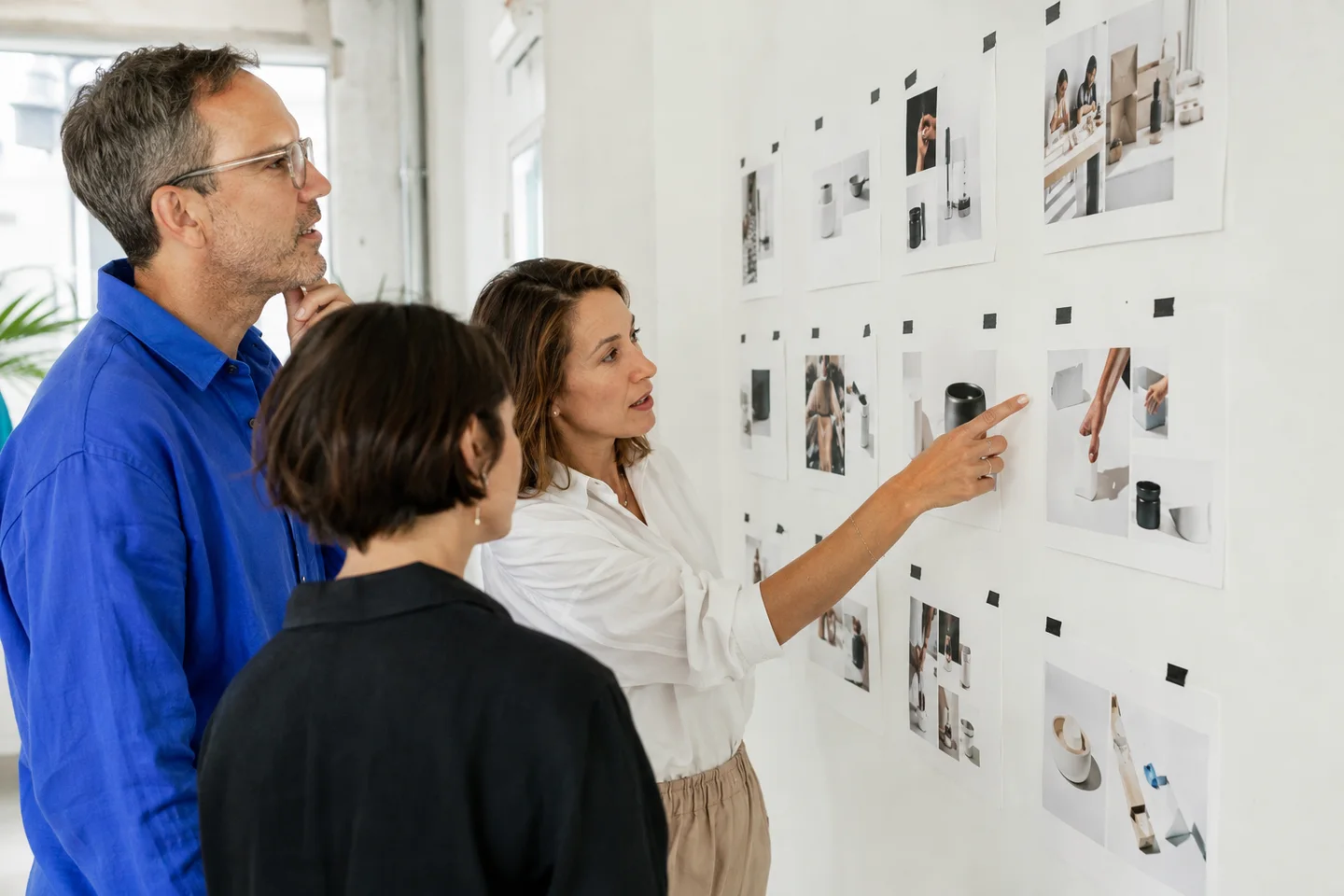 A creative team reviewing product-photo storyboards in a bright studio.