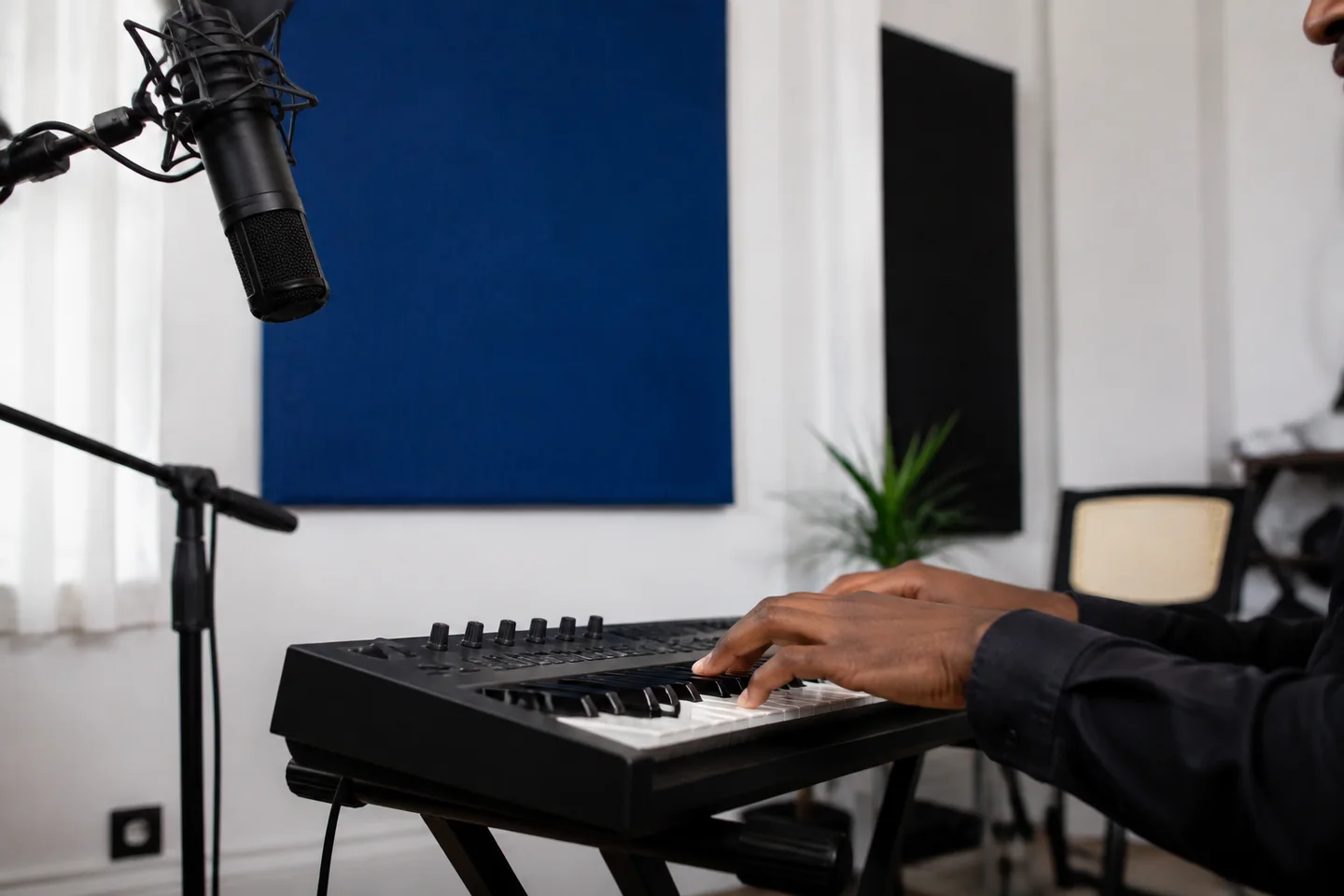 A musician playing keyboard beside a recording microphone.