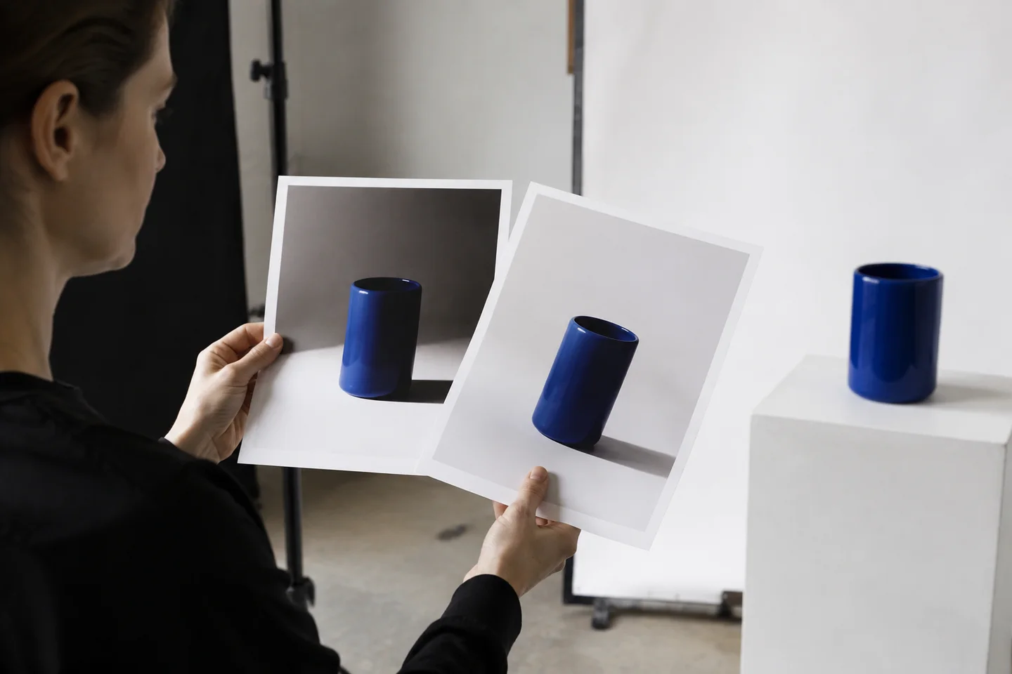 A photographer comparing lighting variants of a plain blue vase.