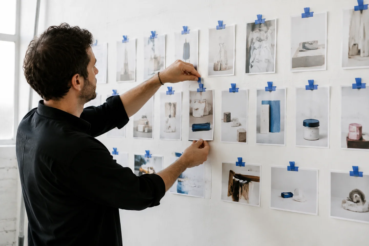 A producer arranging product photographs on a studio planning wall.