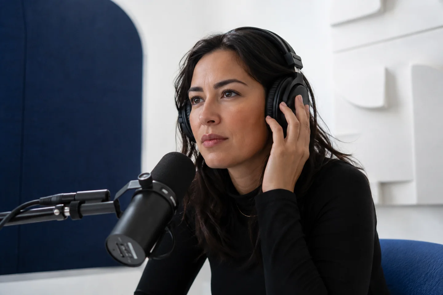 An editor listening closely to recorded speech in a bright audio booth.