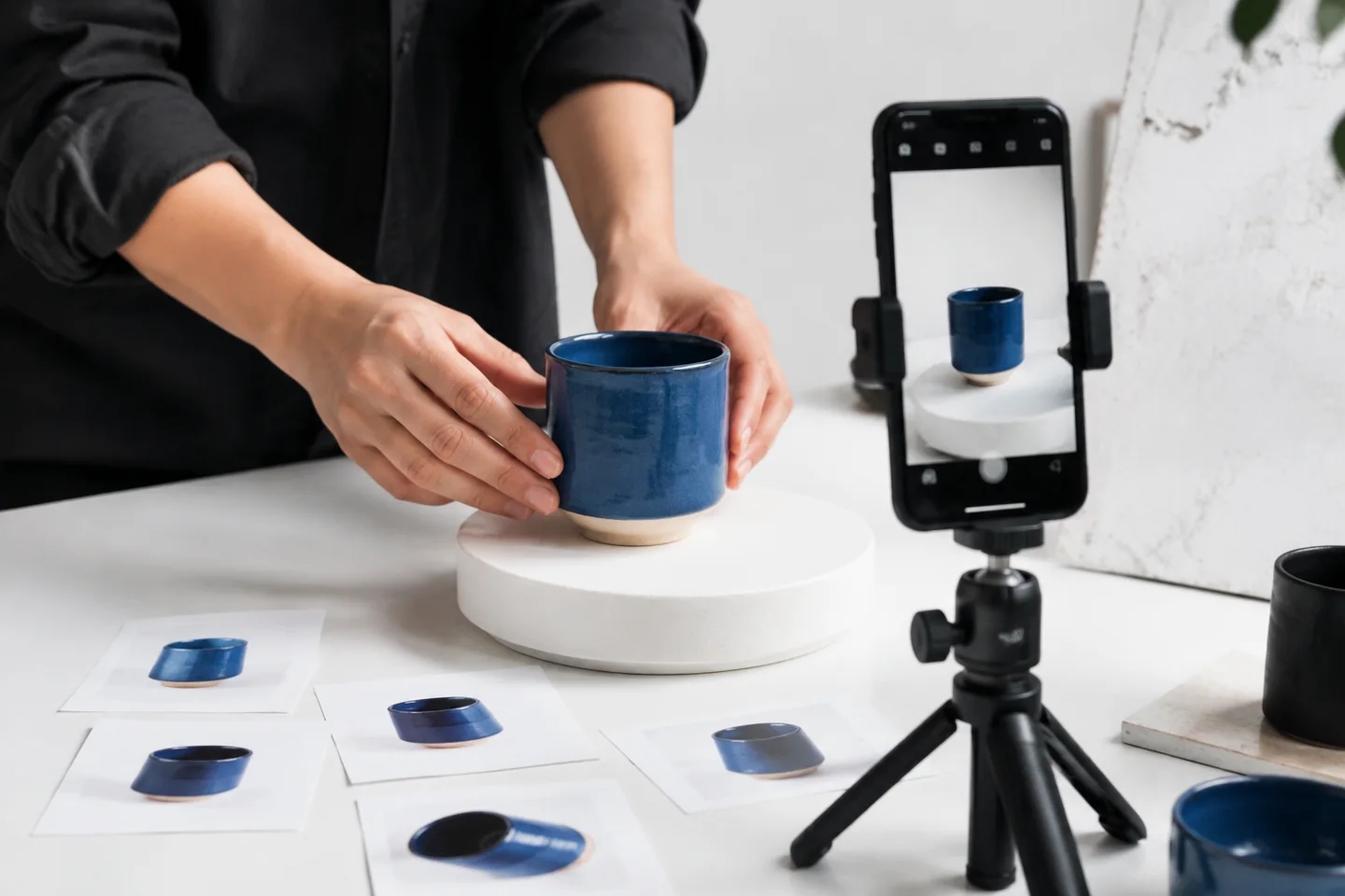 Hands staging a blue ceramic cup for a smartphone product recording.