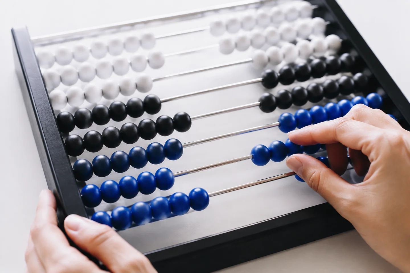 Hands comparing groups of beads on a counting frame.
