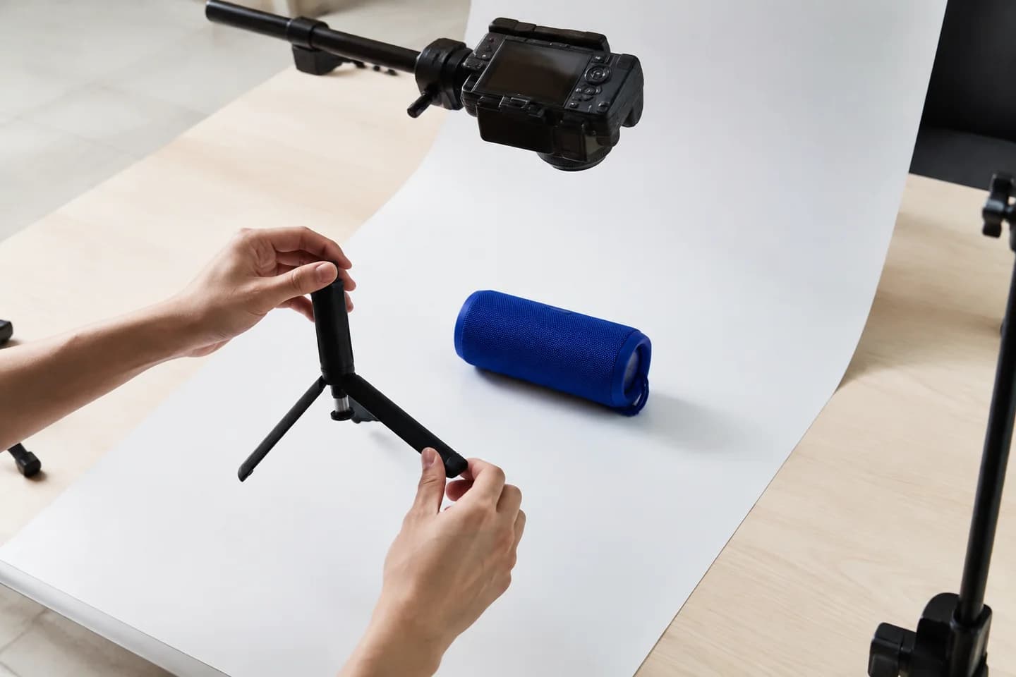 Hands preparing an overhead product-video setup with a blue speaker.